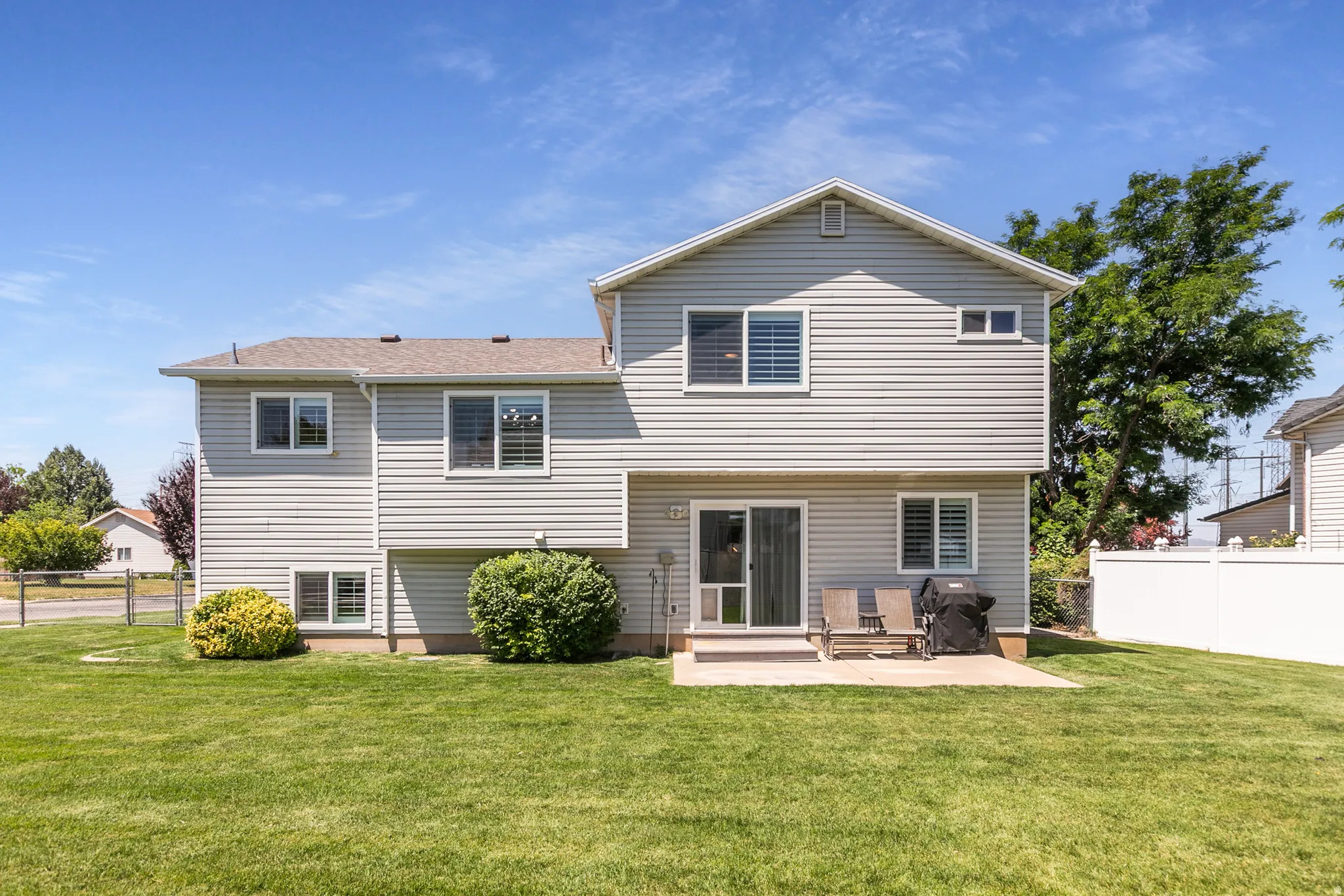 Expansive green lawn surrounds the rear of the property, featuring light-colored siding
