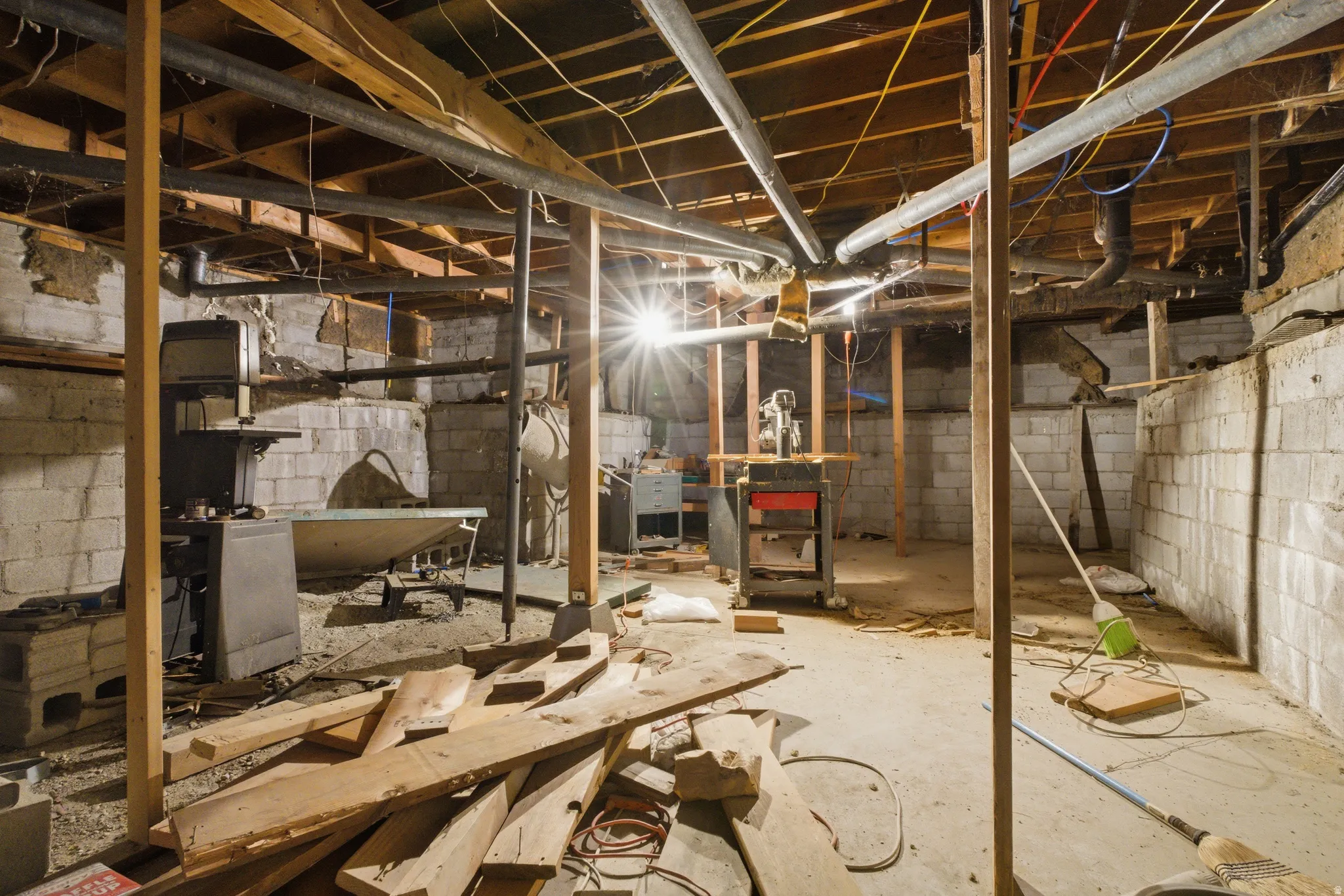 Unfinished basement with exposed wood joists, concrete block walls, and a concrete floor