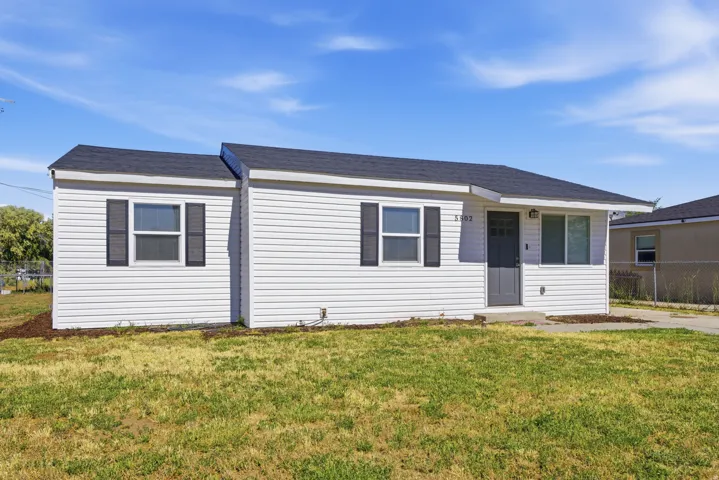 White siding exterior featuring a dark gray entry door, black shutters, and a dark shingle roof