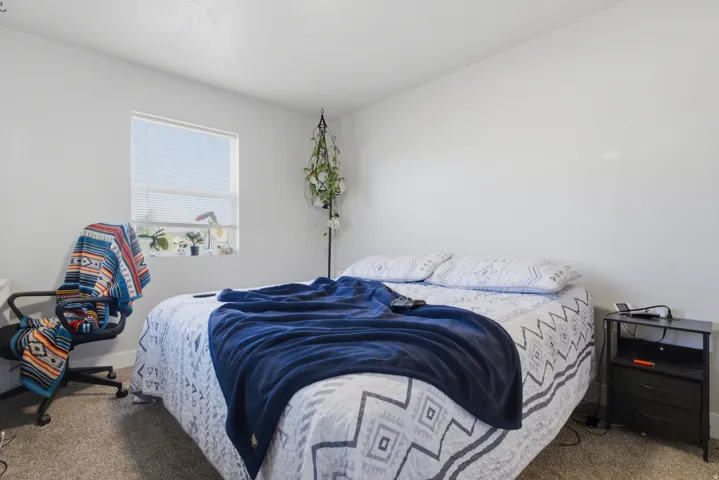 Neutral wall paint with carpeted flooring, featuring a window with blinds