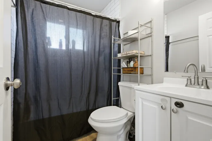 Bathroom with white subway tile, a window, and a white vanity with a single sink and brushed nickel faucet