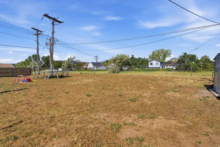 Expansive exterior lot featuring a chain-link fence, a wood privacy fence, and a utility shed with a metal roof