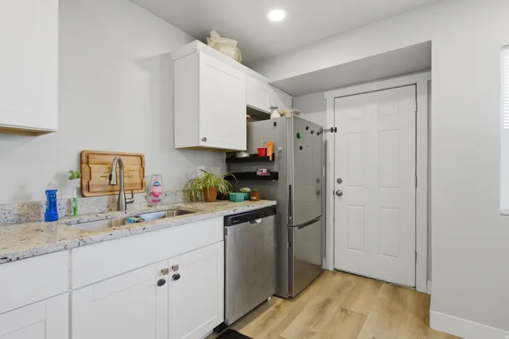 Kitchen area featuring light wood-finish flooring, white cabinetry, and granite-style countertops