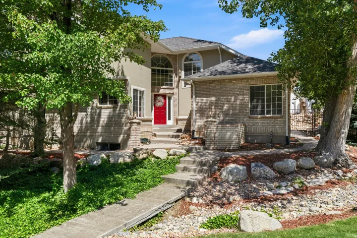 Stately stucco and brick facade with an arched window feature and a vibrant red entry door