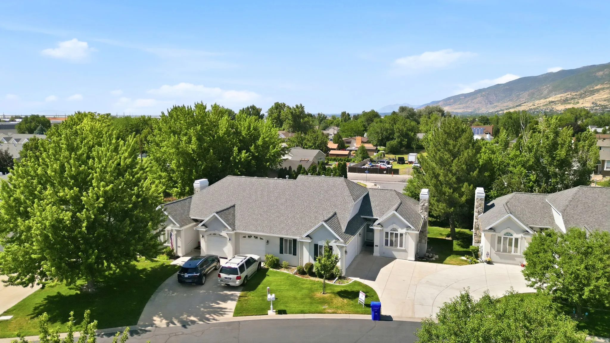 Spacious residential property with a multi-gabled roofline, stone chimneys, and multiple attached garages