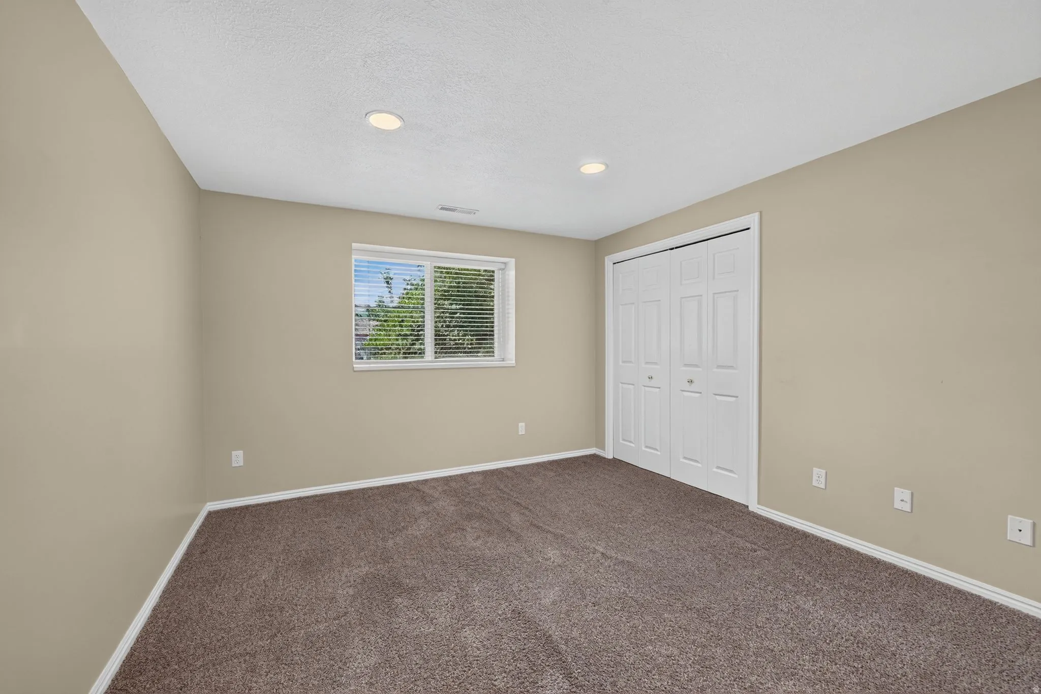 Carpeted room featuring neutral-toned walls, a white trim, and a window with blinds