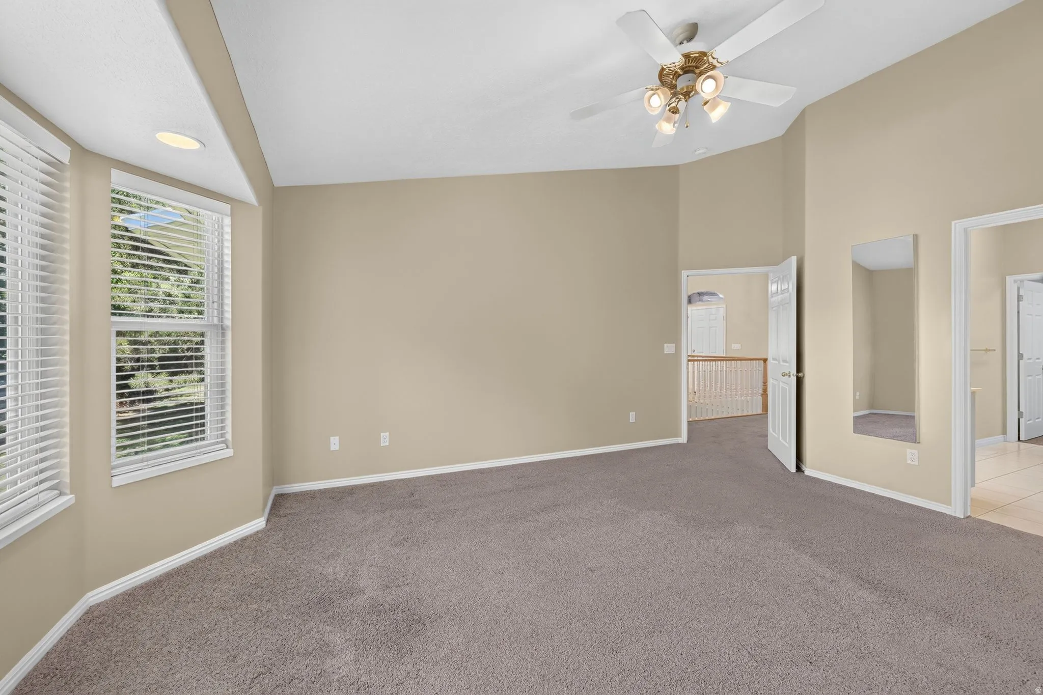 Spacious room featuring vaulted ceilings, a ceiling fan with integrated lighting, recessed lighting, and bay windows