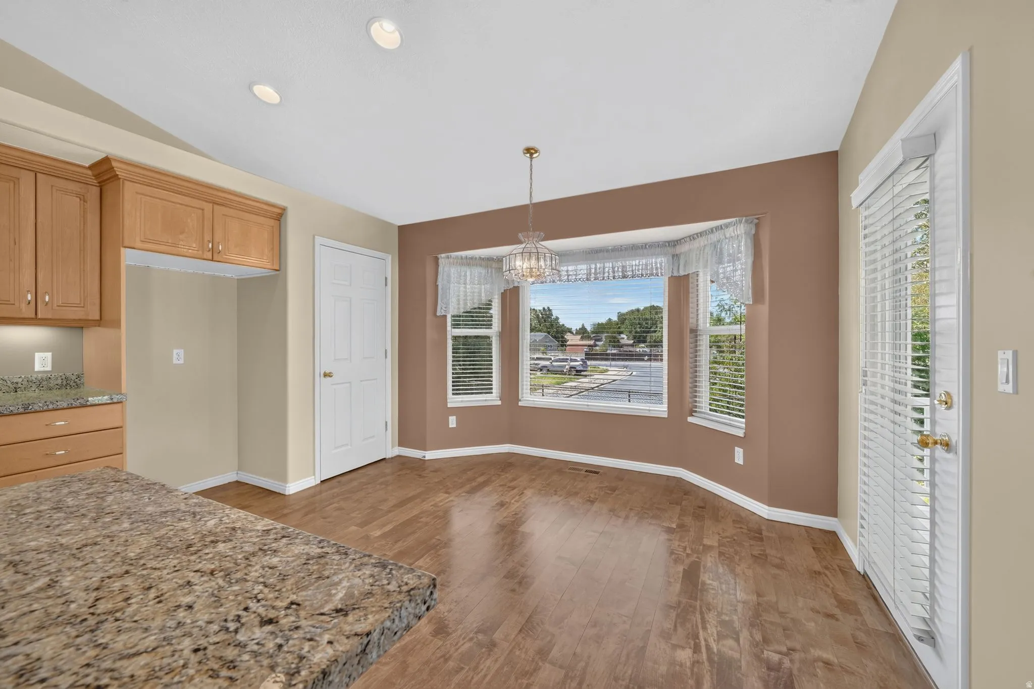 Dining area featuring a bay window, wood-finish flooring, and a decorative chandelier