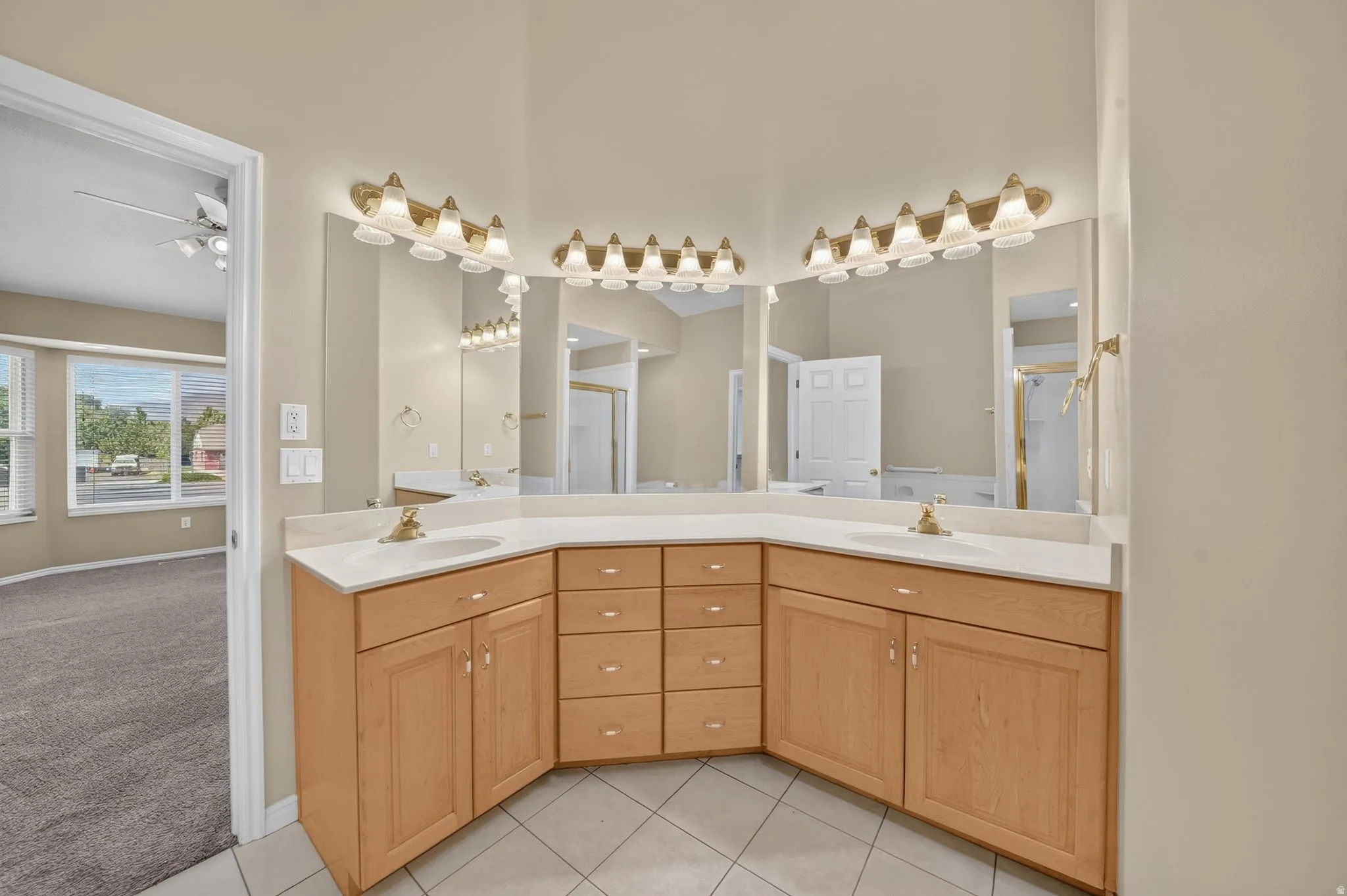 Bathroom vanity featuring dual sinks, a light-toned countertop, and wood-finish cabinetry with both drawers and cabinet storage