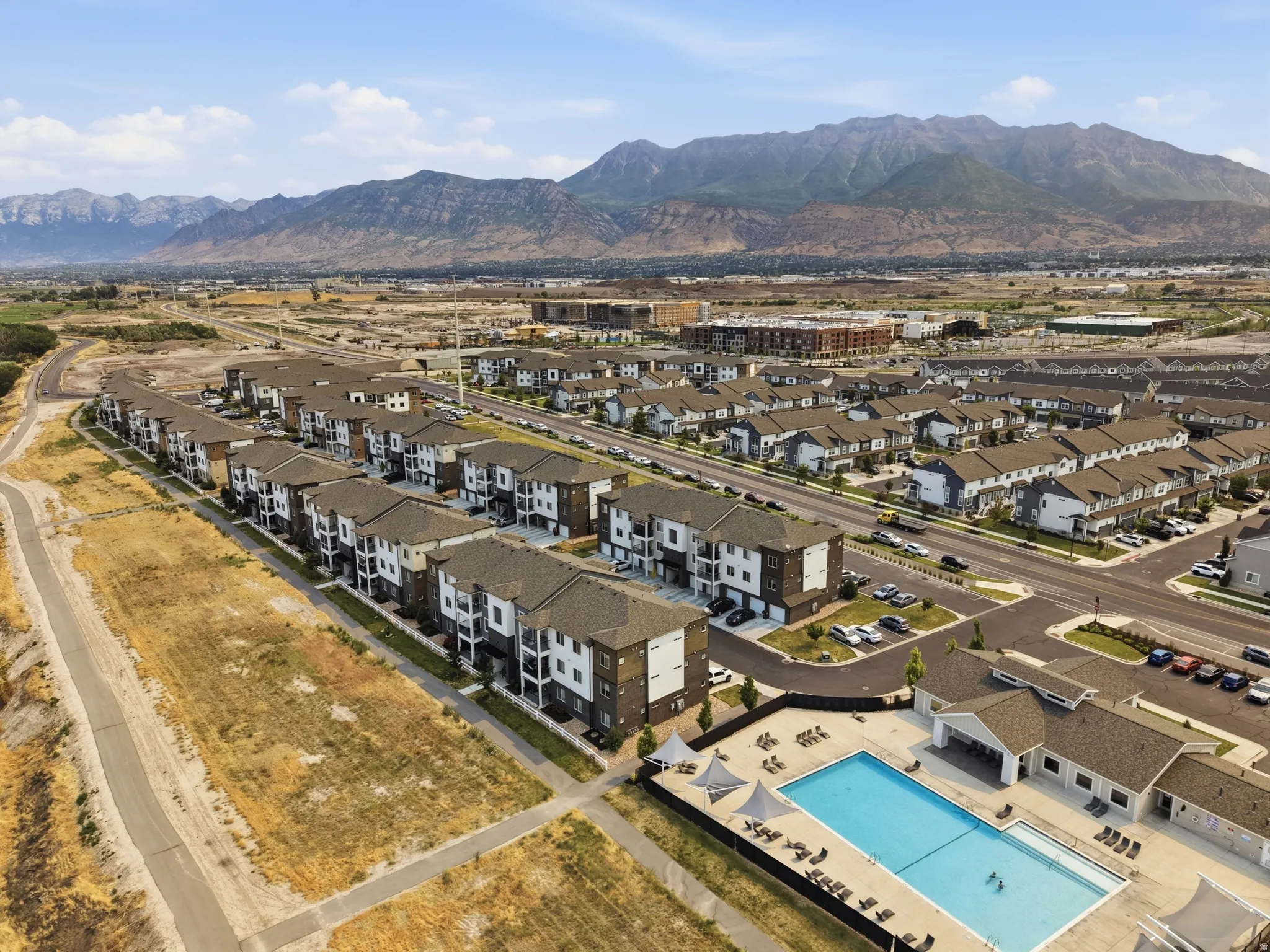 Aerial perspective showcasing a community with multi-level residential buildings featuring dark roofing and light and dark facade elements