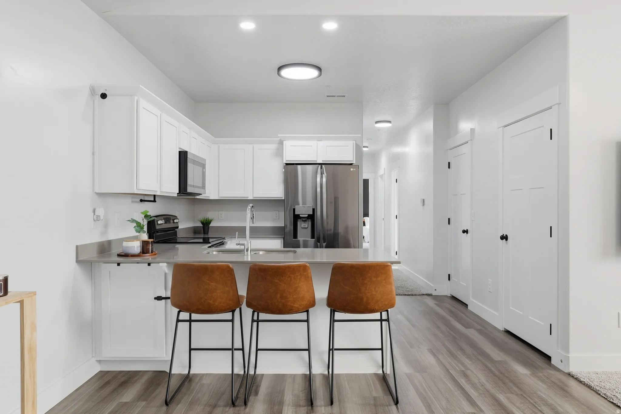Modern kitchen featuring white cabinetry, stainless steel appliances, and a gray countertop with an integrated sink