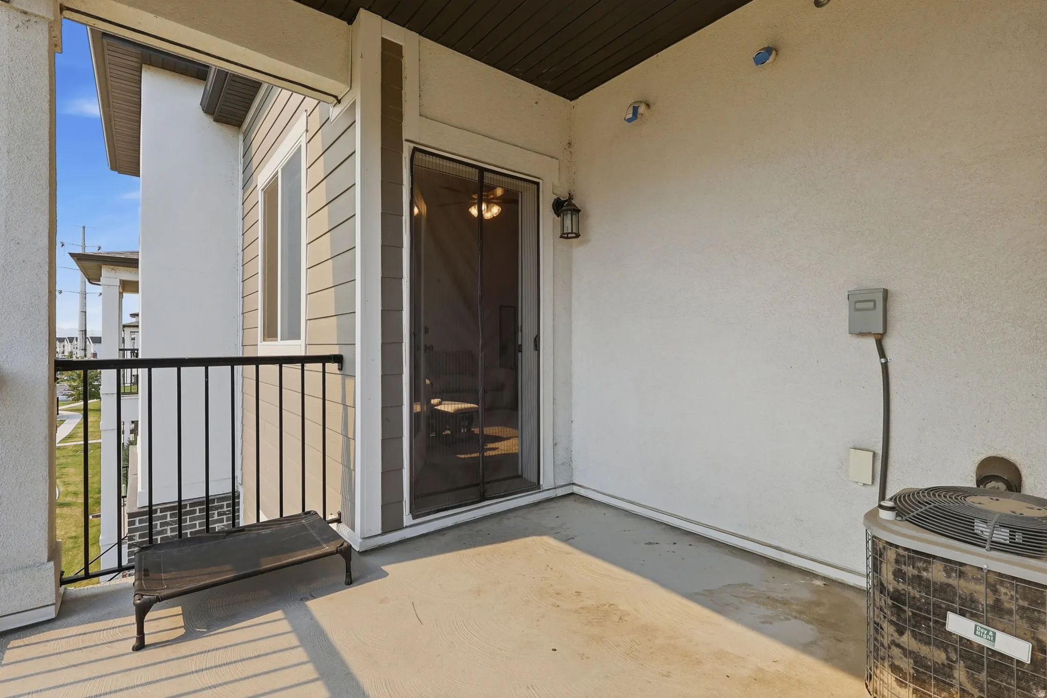 Private balcony featuring a concrete floor, black metal railing, and a stucco exterior wall