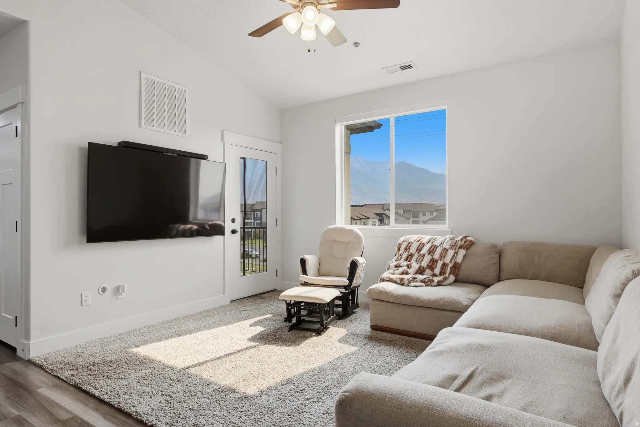 Spacious living area featuring a vaulted ceiling and wood-finish ceiling fan