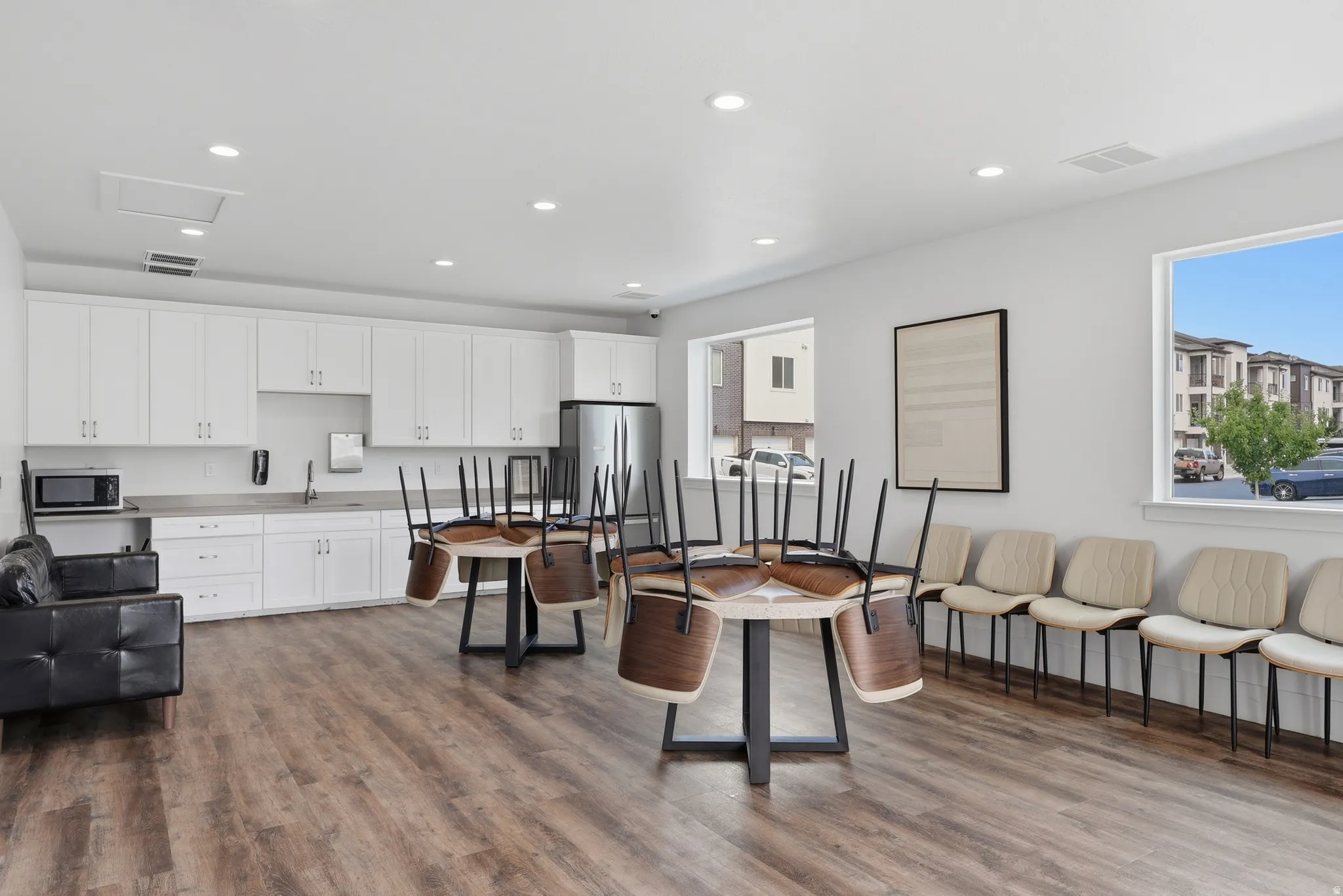 Spacious common area featuring wood-finish flooring, white cabinetry, light countertops, and recessed lighting