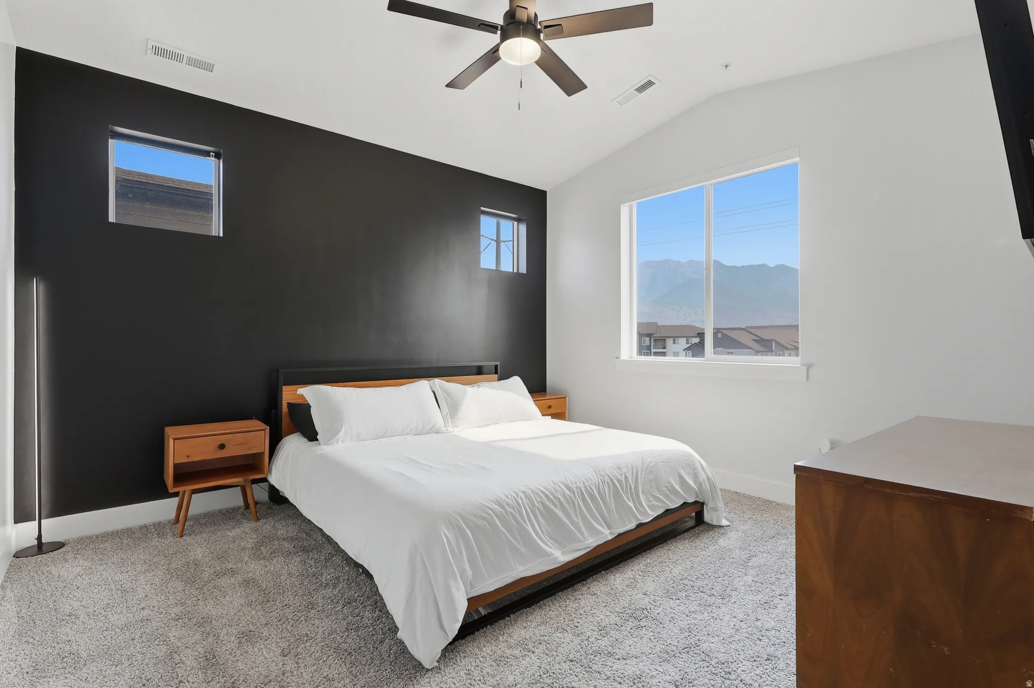 Spacious room featuring a vaulted ceiling with a ceiling fan, a large window with mountain scenery, and two high wall windows