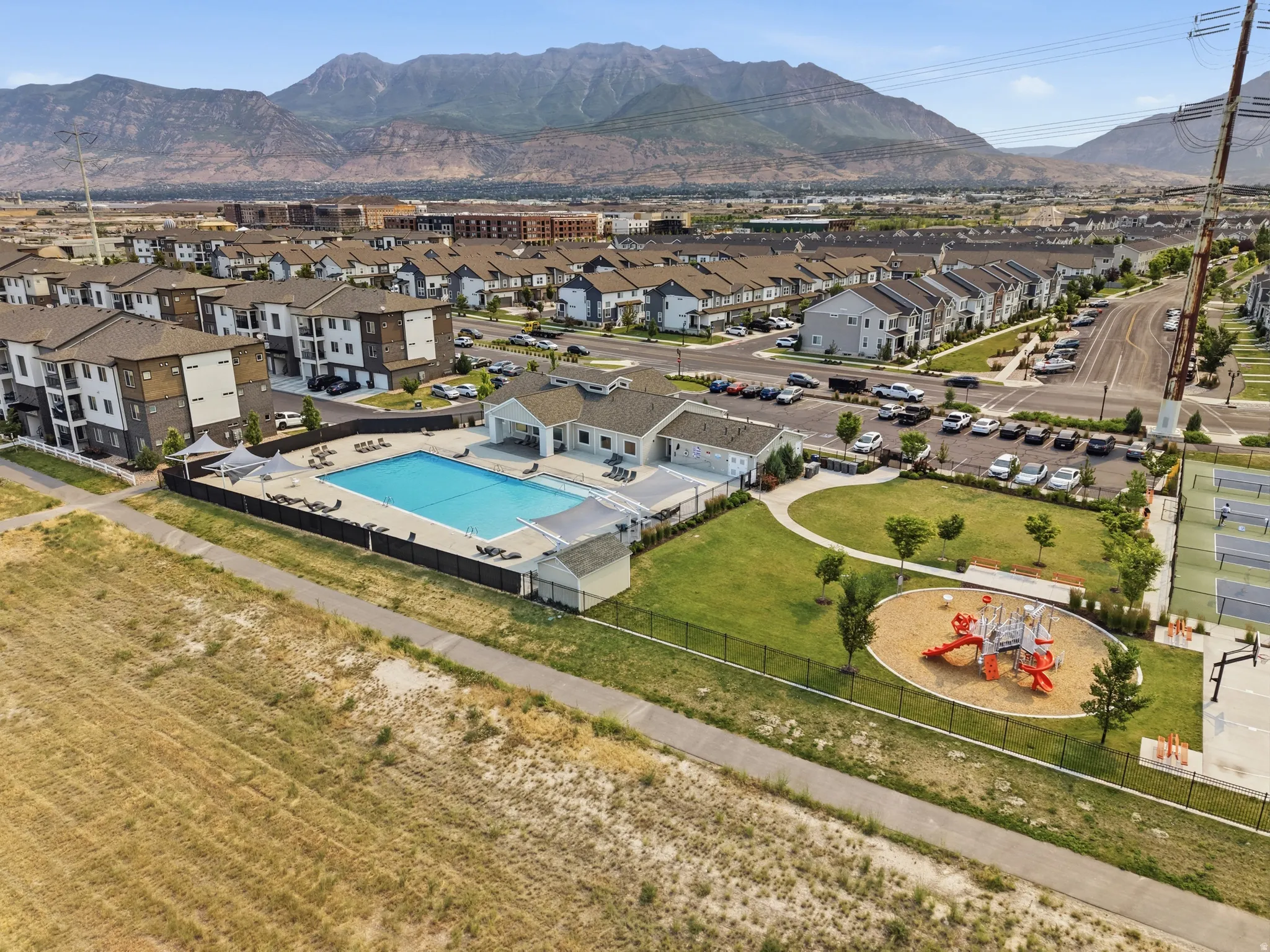 Community amenities featuring a swimming pool, shaded lounge areas, a playground, and sports courts