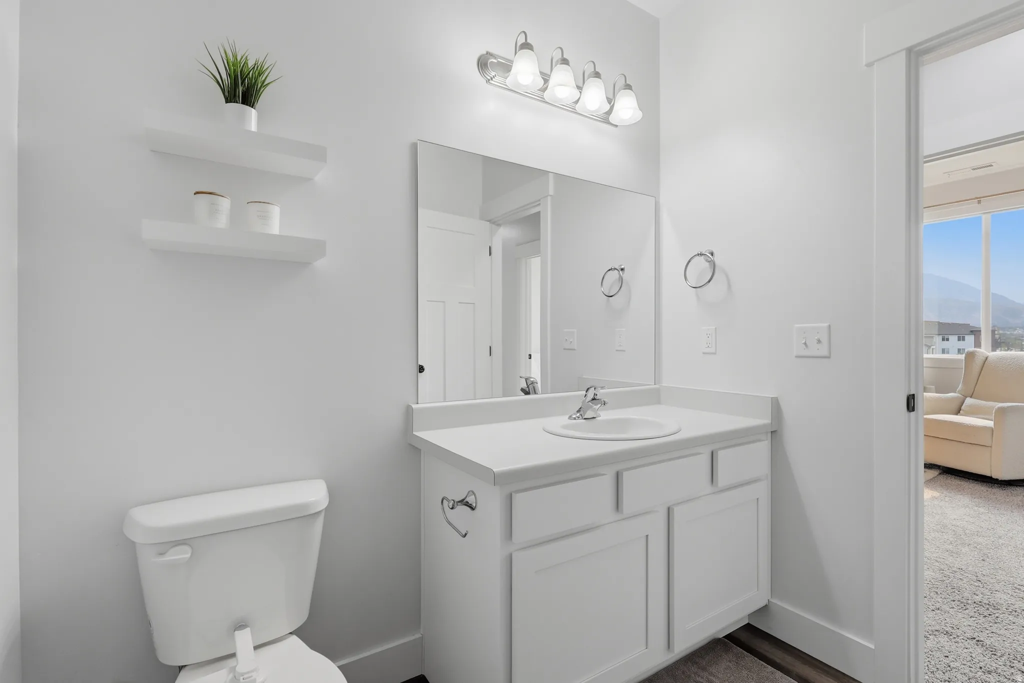 Bathroom featuring a single vanity with an integrated sink, white cabinetry, a large wall-mounted mirror, and a five-light fixture