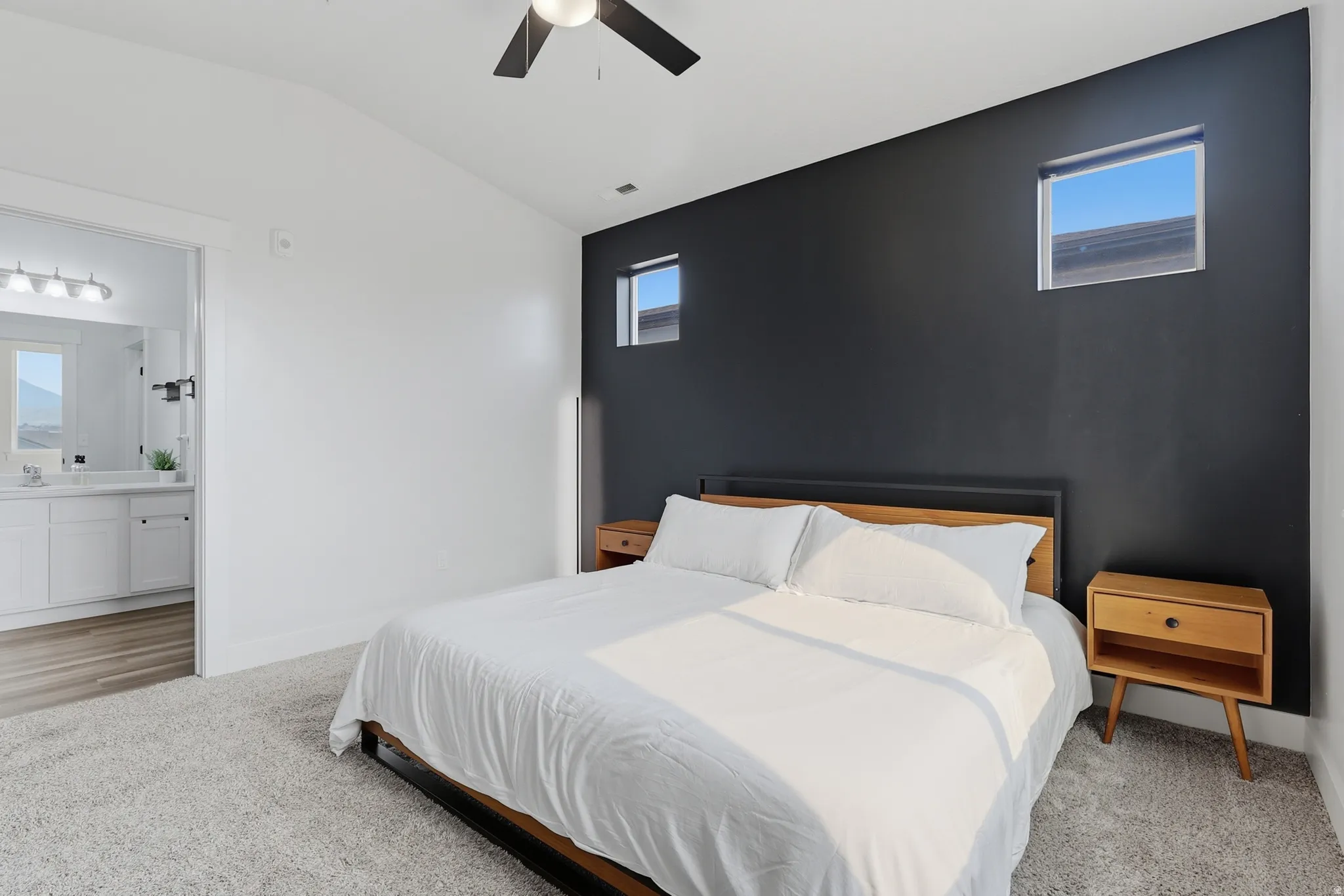 Spacious room featuring vaulted ceilings, a contemporary ceiling fan, and a striking accent wall with two high windows