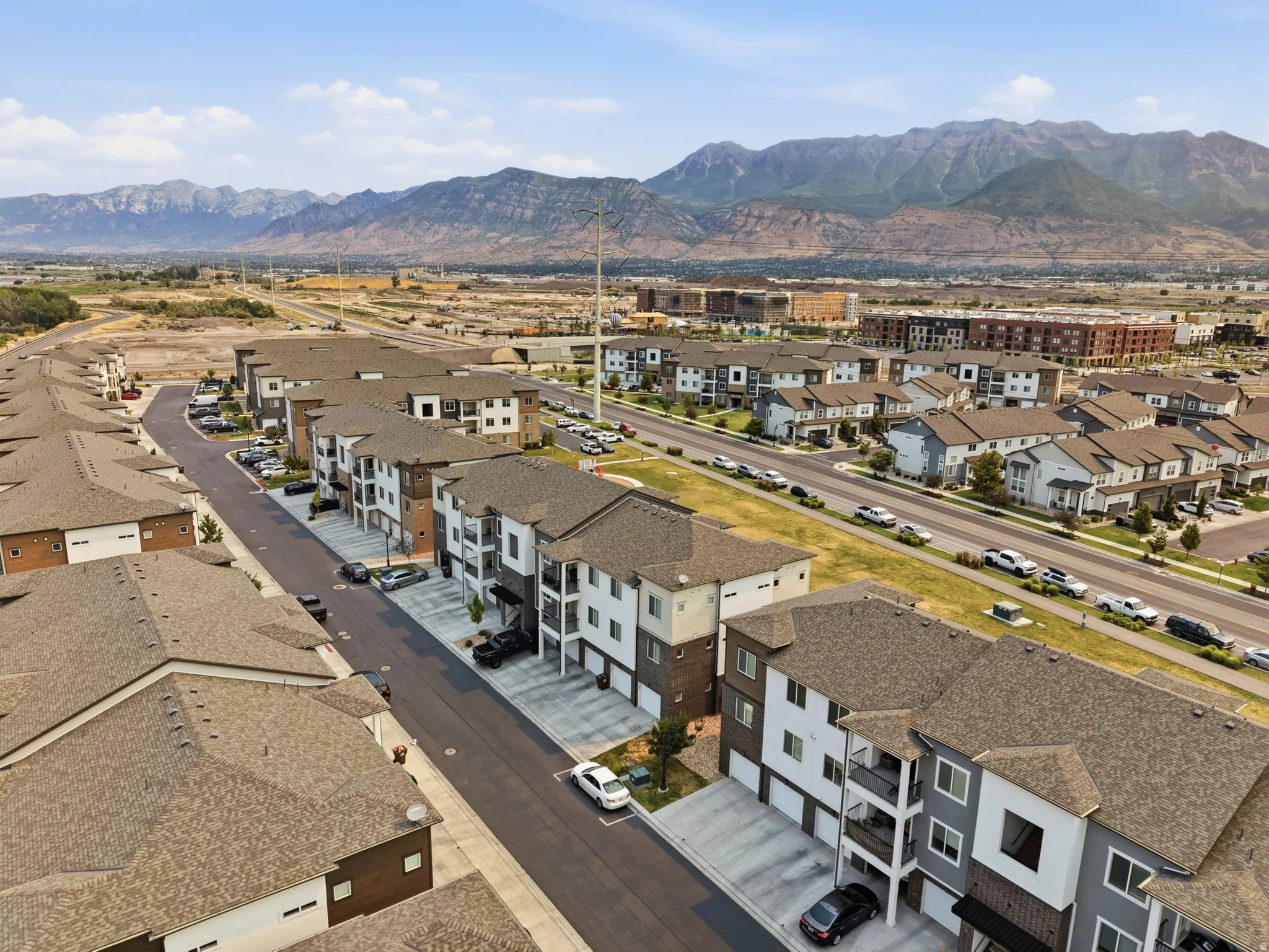 New construction multi-story buildings featuring balconies, attached garages, and a mountain backdrop