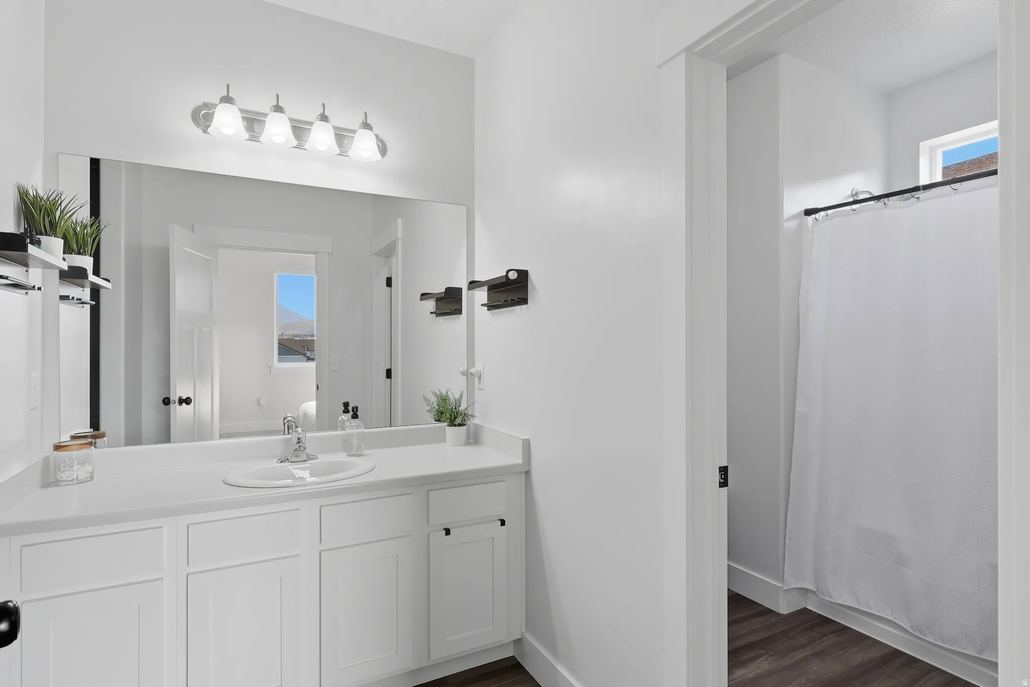 Contemporary bathroom featuring a white vanity with integrated sink, a large wall-mounted mirror, and a chrome light fixture