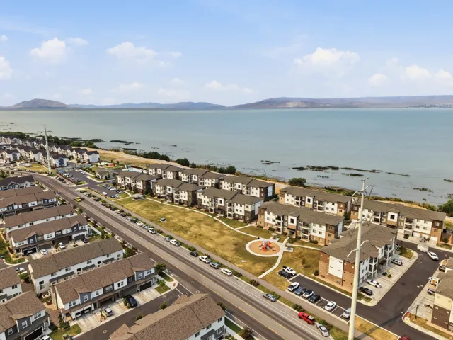 Aerial perspective showcasing a residential community bordering a large body of water with distant mountains