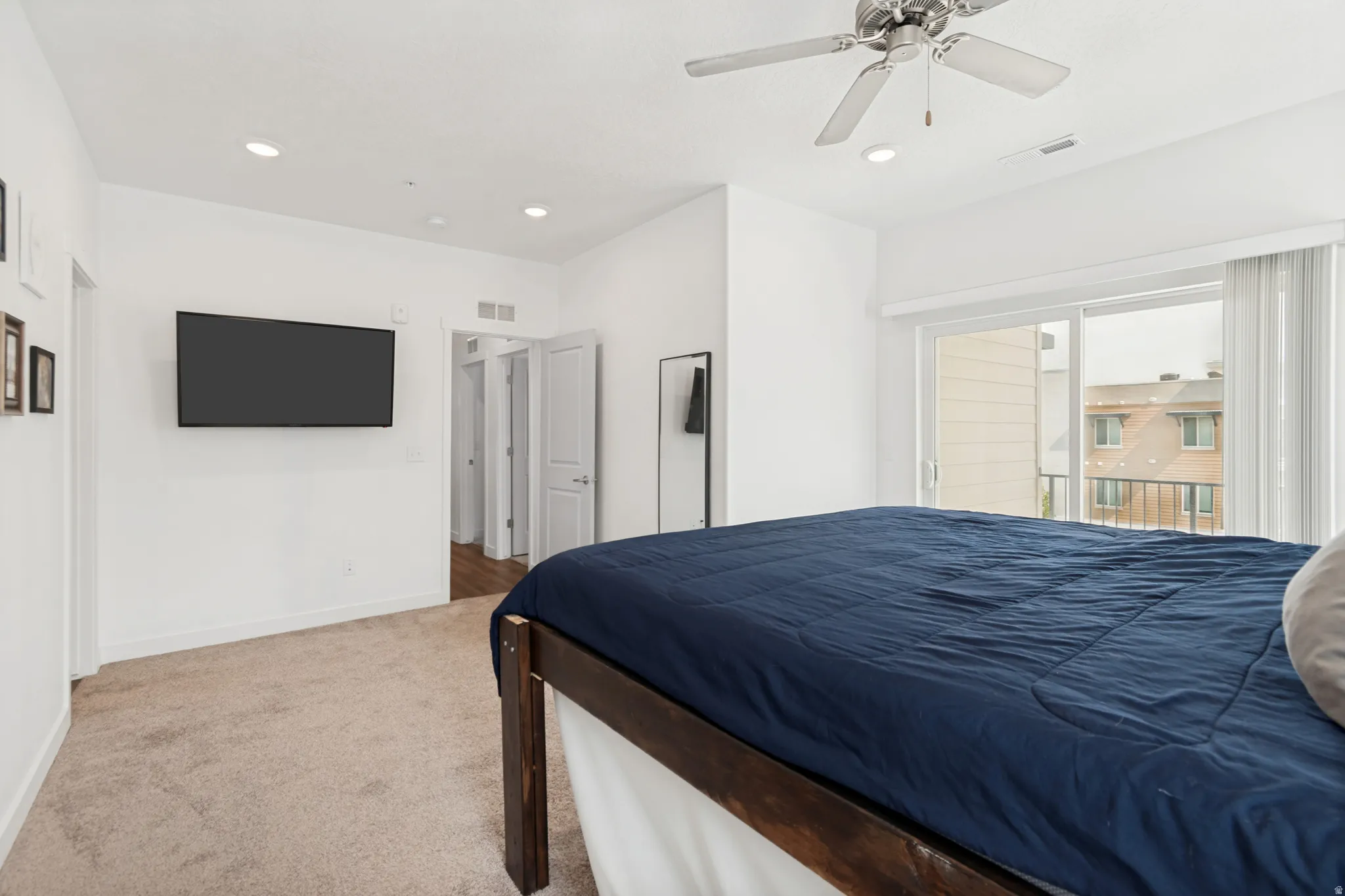 Bedroom 3 featuring a ceiling fan, recessed lighting, wall-mounted television, and sliding glass door leading to a balcony with metal railings