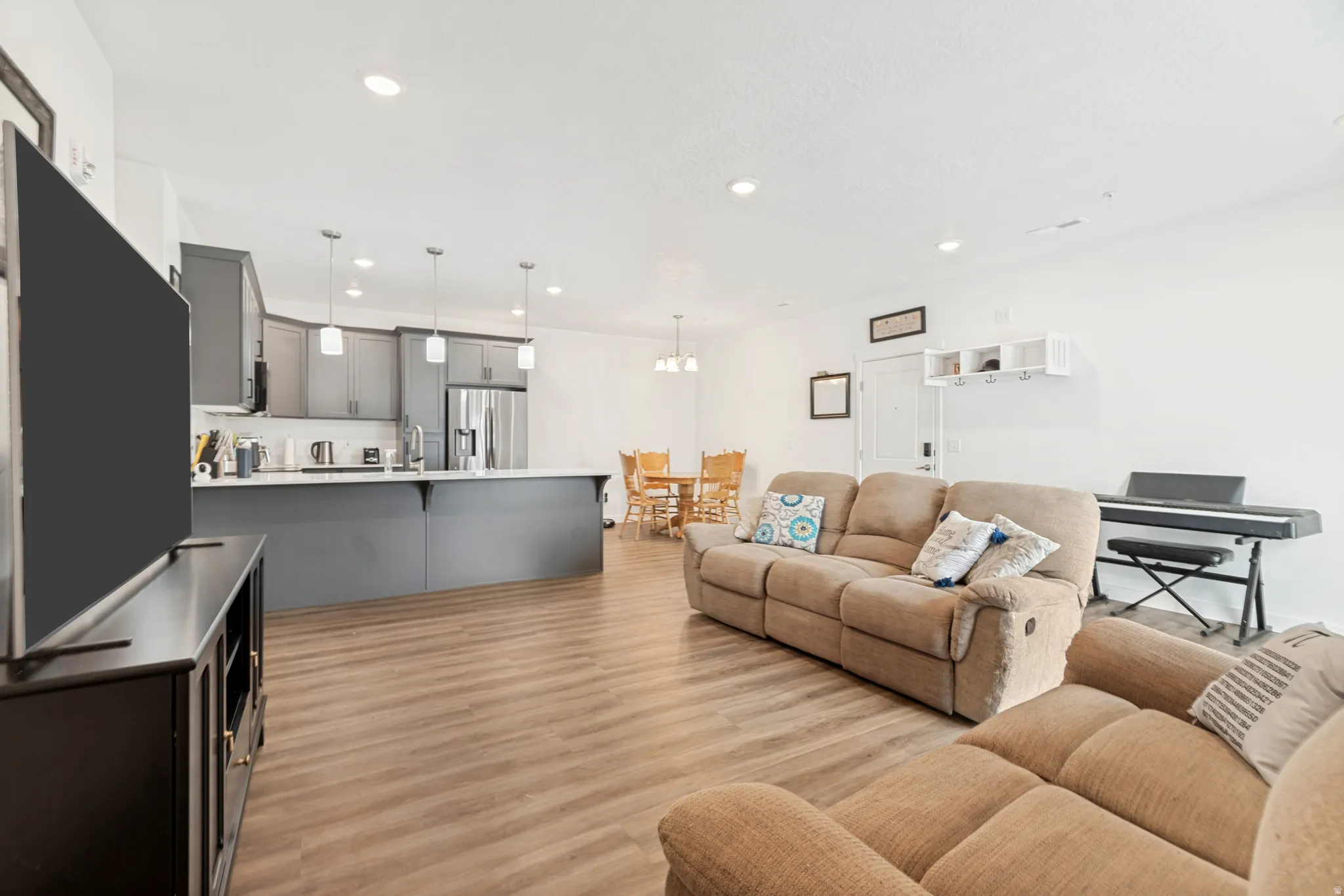 Open-concept living space featuring wood-finish flooring, recessed lighting, and a neutral color palette