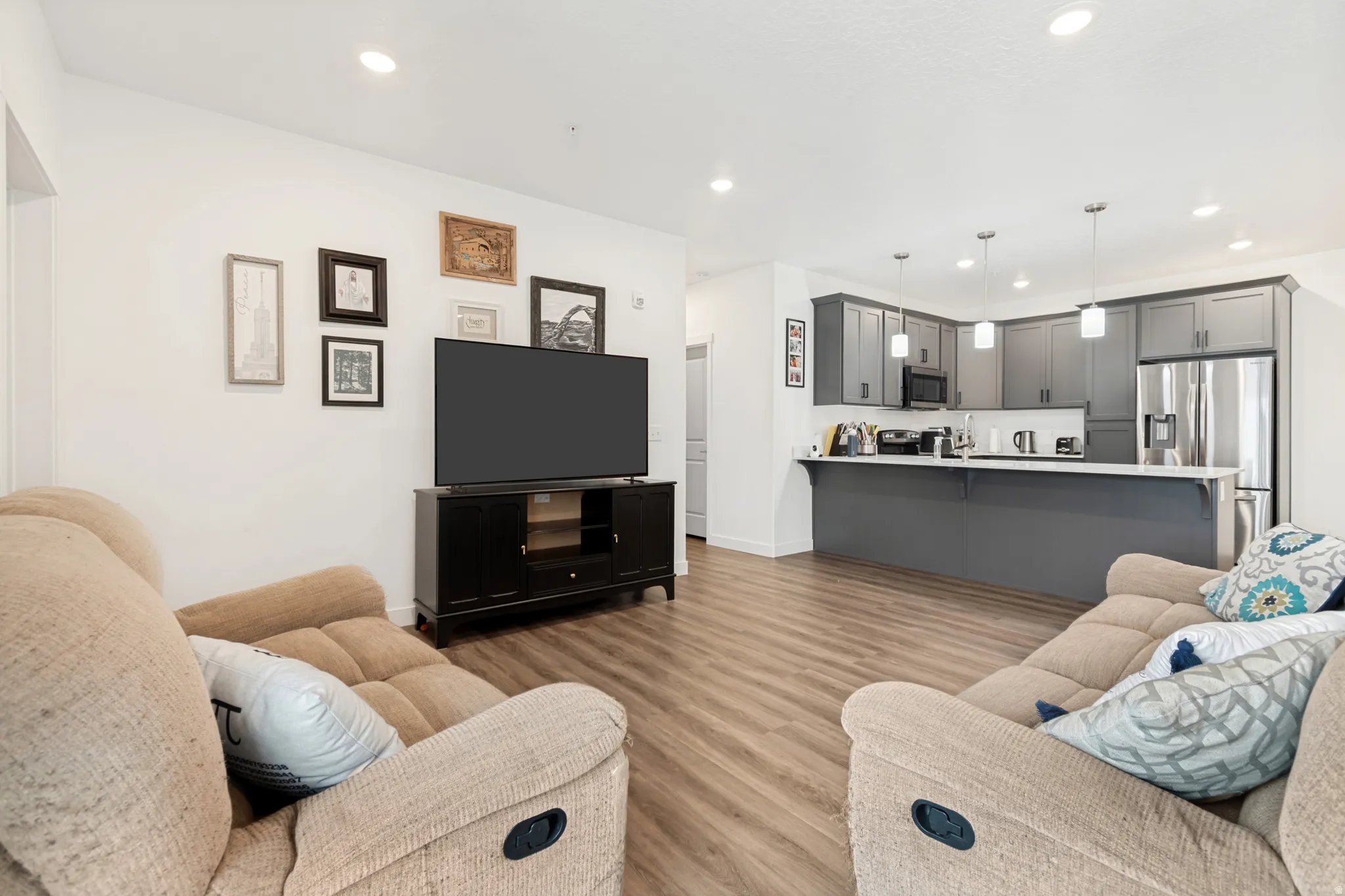 Open-concept living space featuring wood-finish flooring, recessed lighting, and a neutral color palette