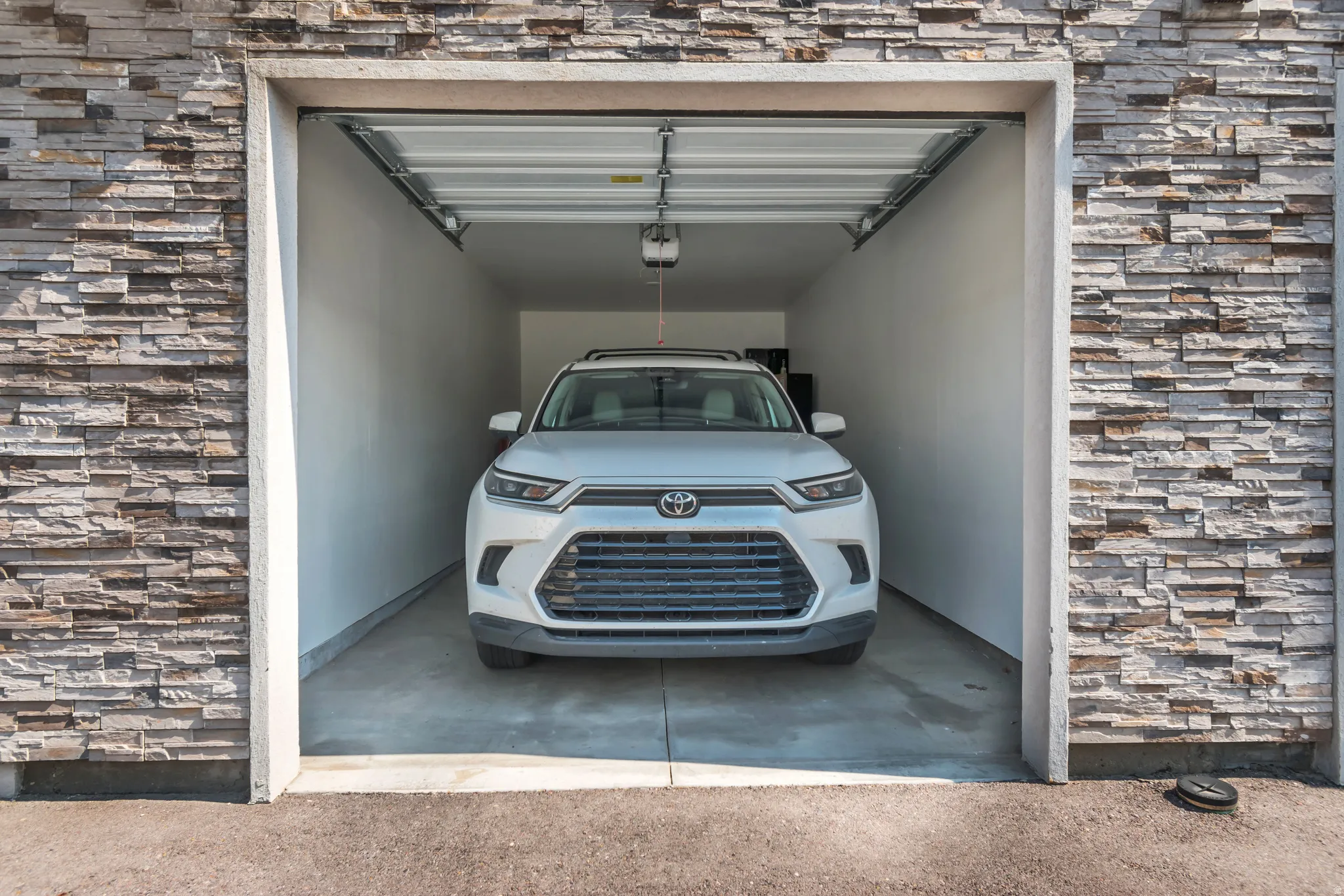 Single-bay garage featuring an automatic door opener, finished interior walls, and a concrete floor