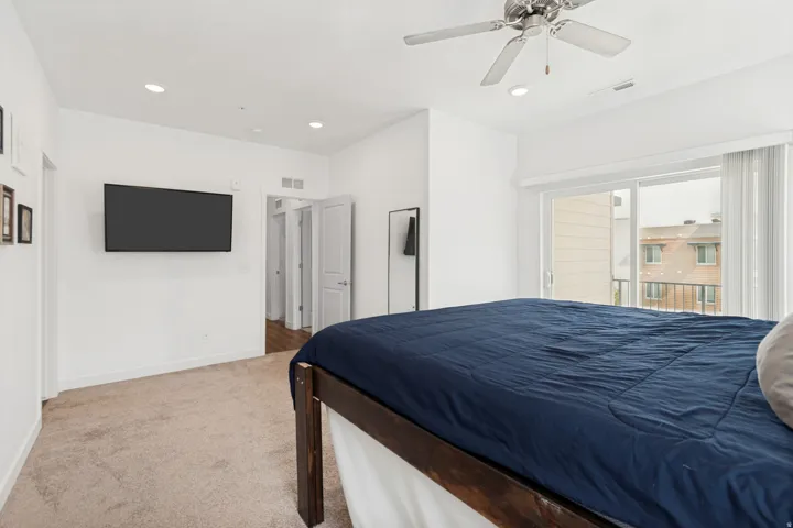 Bedroom 3 featuring a ceiling fan, recessed lighting, wall-mounted television, and sliding glass door leading to a balcony with metal railings