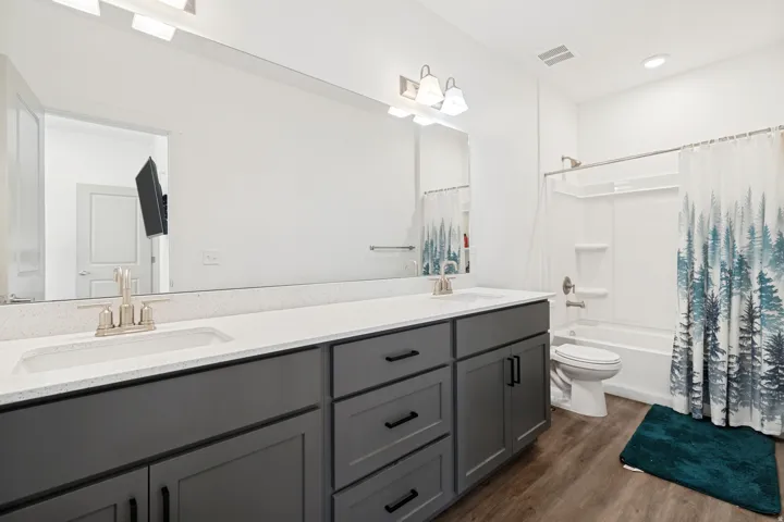 Primary bathroom with double vanity featuring gray cabinetry, integrated sinks, and a light-toned countertop