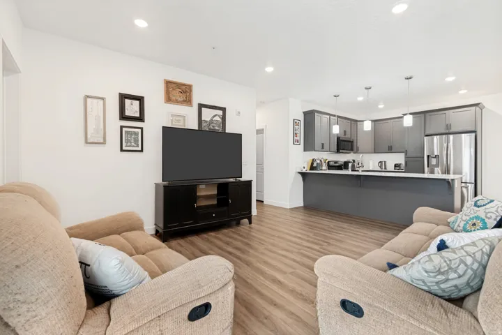 Open-concept living space featuring wood-finish flooring, recessed lighting, and a neutral color palette