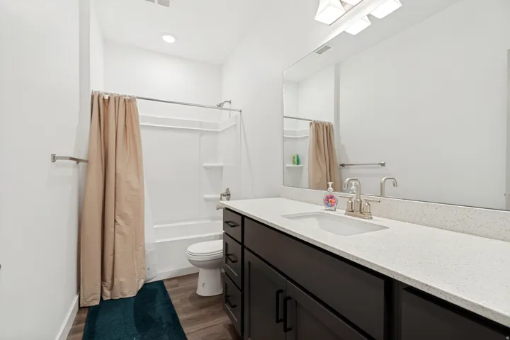 Bathroom featuring a dark wood-finish vanity with a light speckled countertop, an undermount sink, and a large mirror