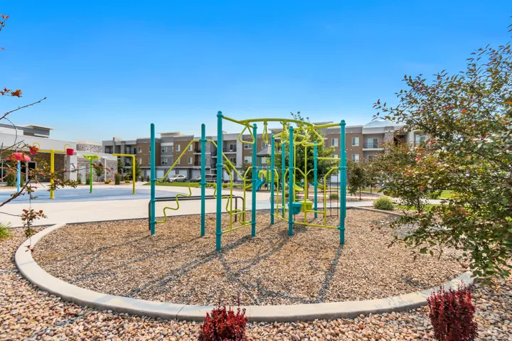 Community playground featuring modern climbing structures, a poured-in-place rubber surface, and surrounding landscaping with decorative gravel and shrubbery