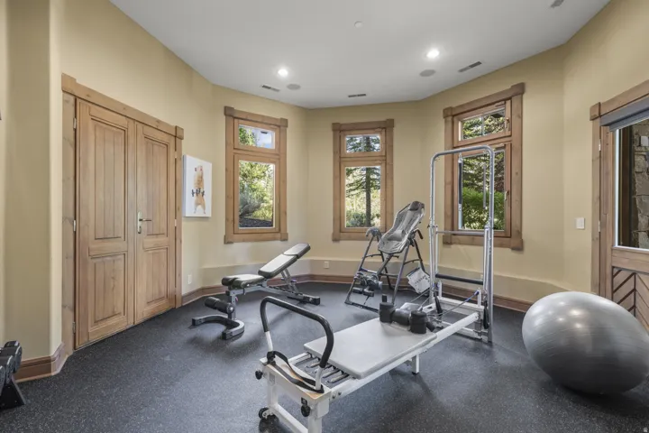 Dedicated fitness room featuring durable rubber flooring, recessed lighting, and multiple windows with natural wood trim