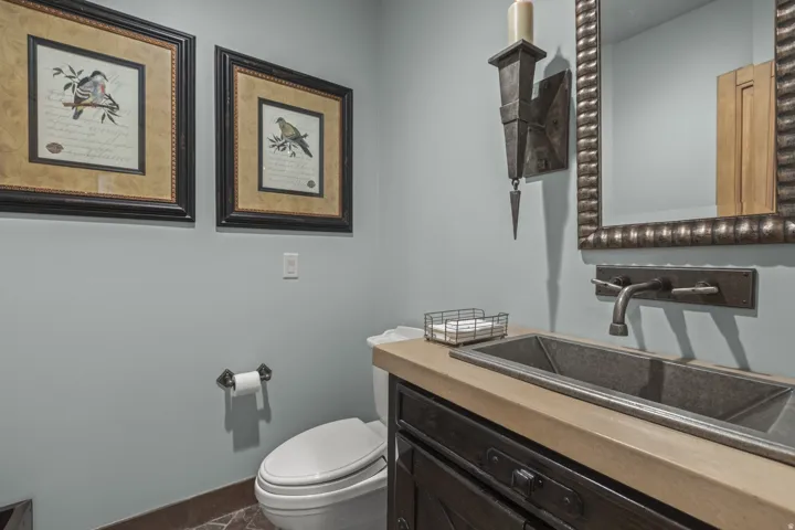 Powder room featuring a rectangular basin sink, wall-mounted faucet, and a wall sconce
