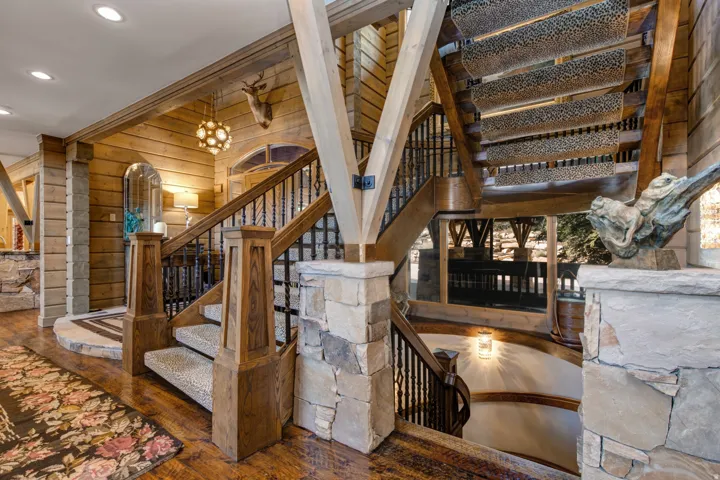 Multi-level staircase featuring wood-finish flooring, stone accents, and wrought iron balusters
