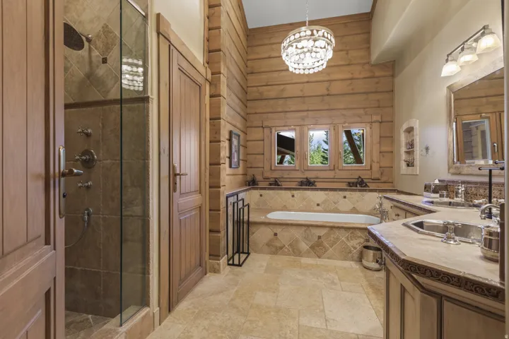 Expansive bathroom featuring a glass-enclosed shower, a large soaking tub, and a double vanity with stone countertops