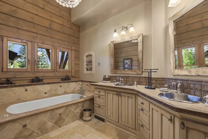 Bathroom featuring a built-in soaking tub with stone surround, wood-paneled walls, and a multi-window configuration