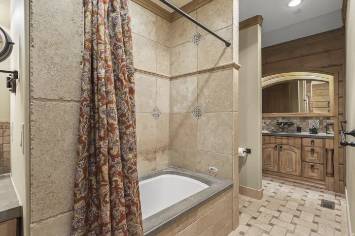 Bathroom featuring a tiled tub surround with decorative accents, an integrated bathtub, and a tiled floor