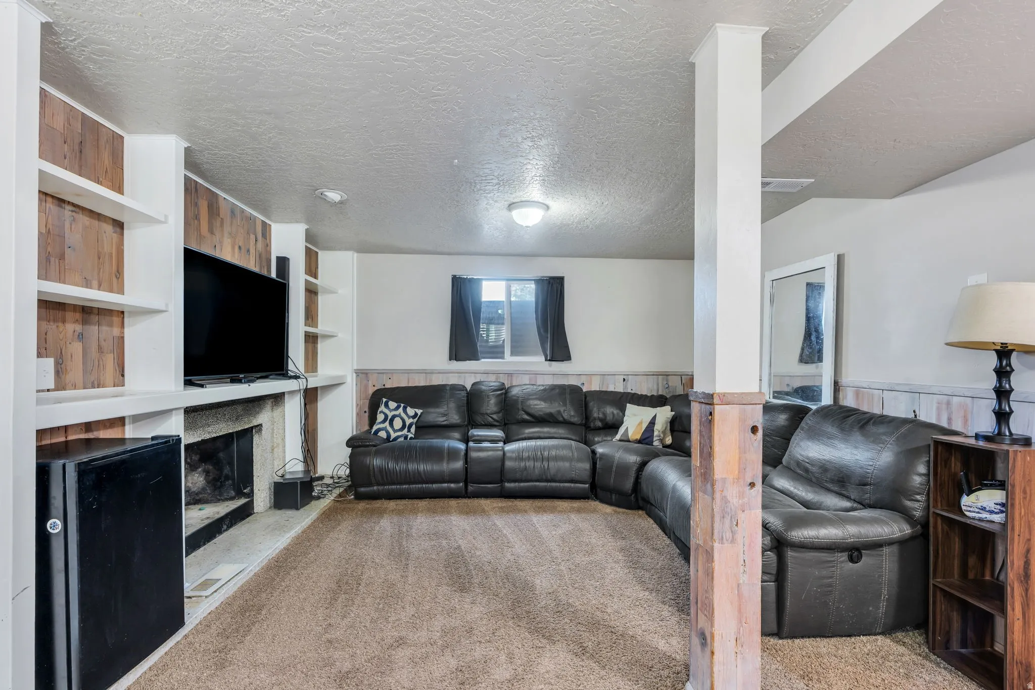 Recessed living space featuring built-in shelving, wood-finish accent wall, and a fireplace with a stone hearth