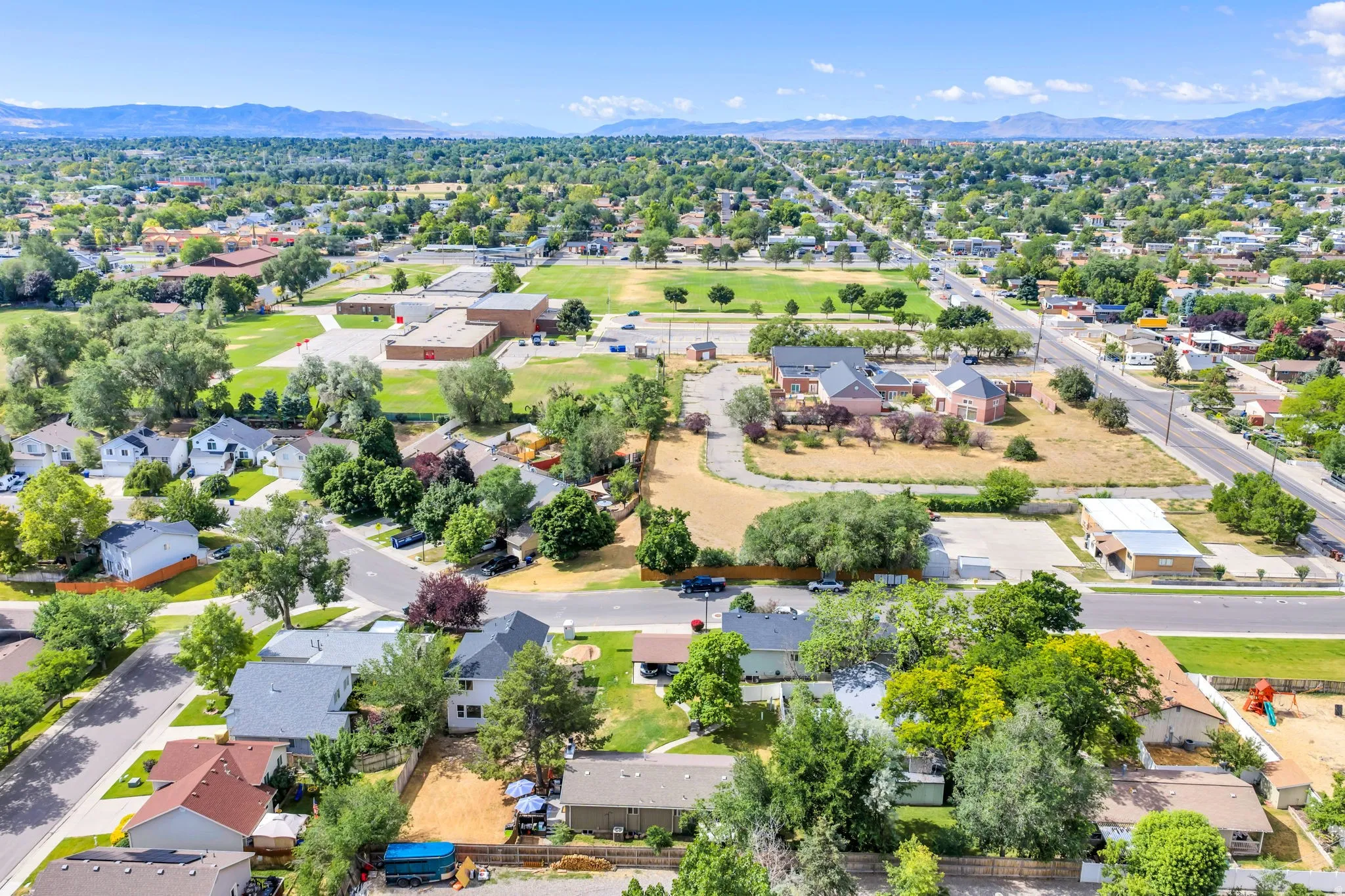 Aerial perspective showcasing a residential area with varied housing styles, mature trees, and paved streets