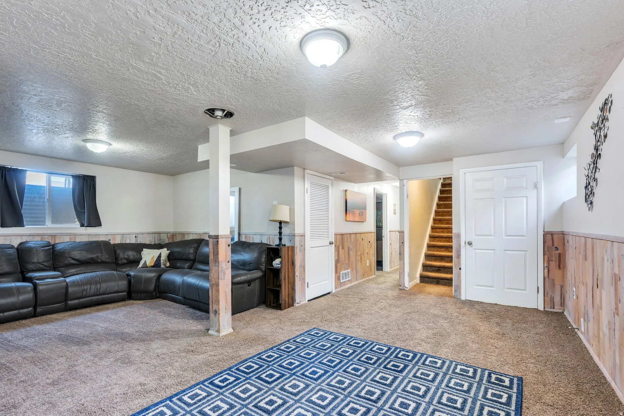 Carpeted interior space featuring wood-finish wainscoting, a carpeted staircase, and multiple flush-mount ceiling lights