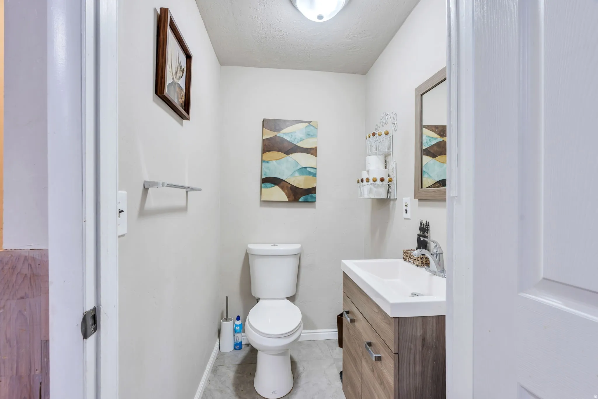 Neutral-toned bathroom featuring a wood-finish vanity with a white countertop and rectangular sink