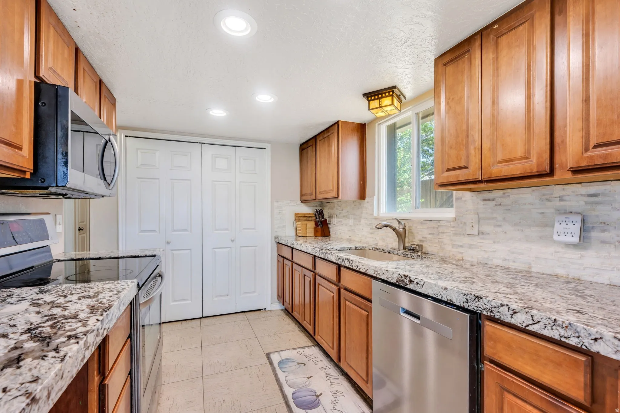 Kitchen featuring wood cabinetry, granite countertops, tile flooring, and a subway tile backsplash