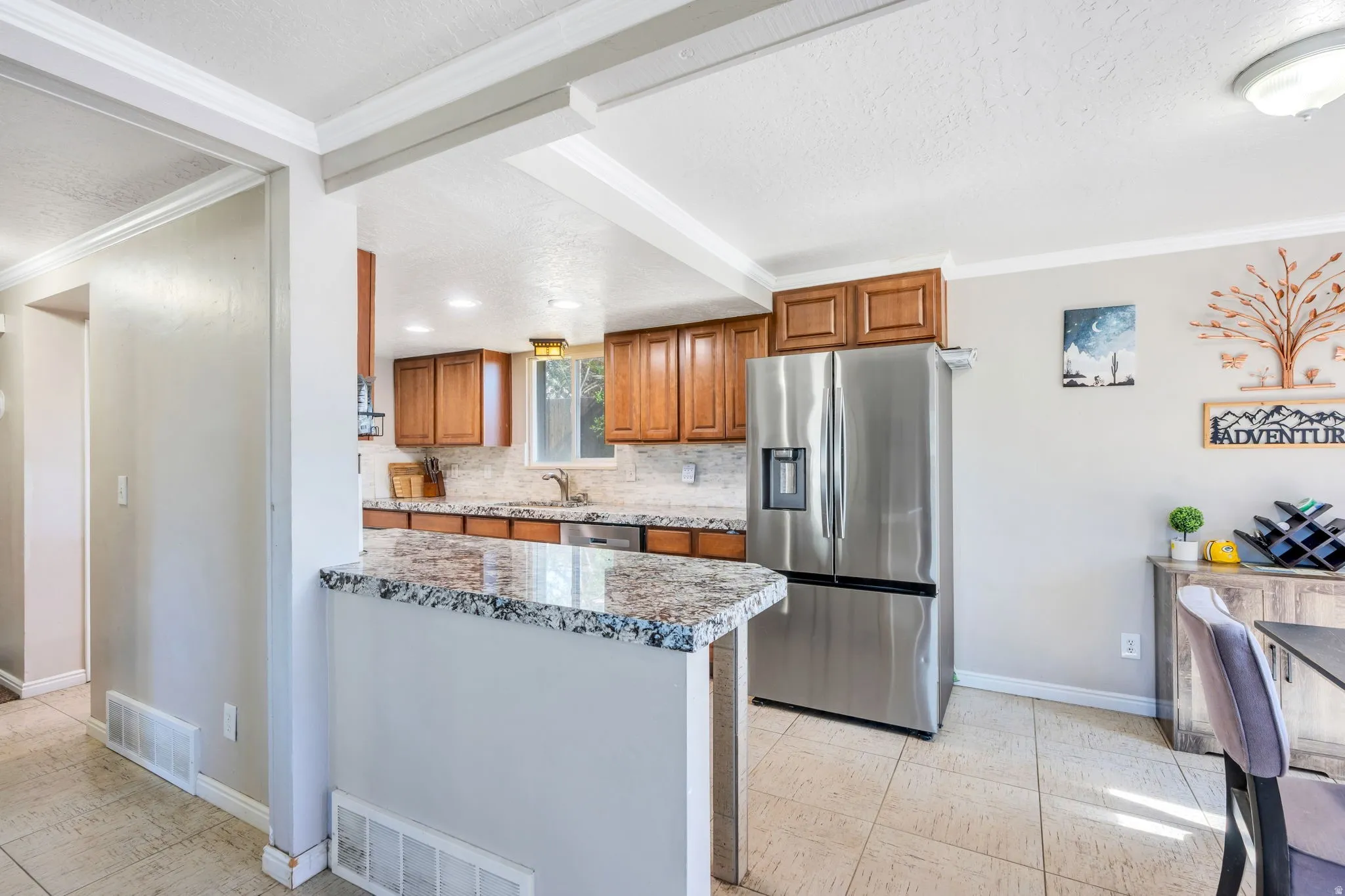 Kitchen featuring rich wood cabinetry, stainless steel appliances, speckled stone countertops, and a tile backsplash