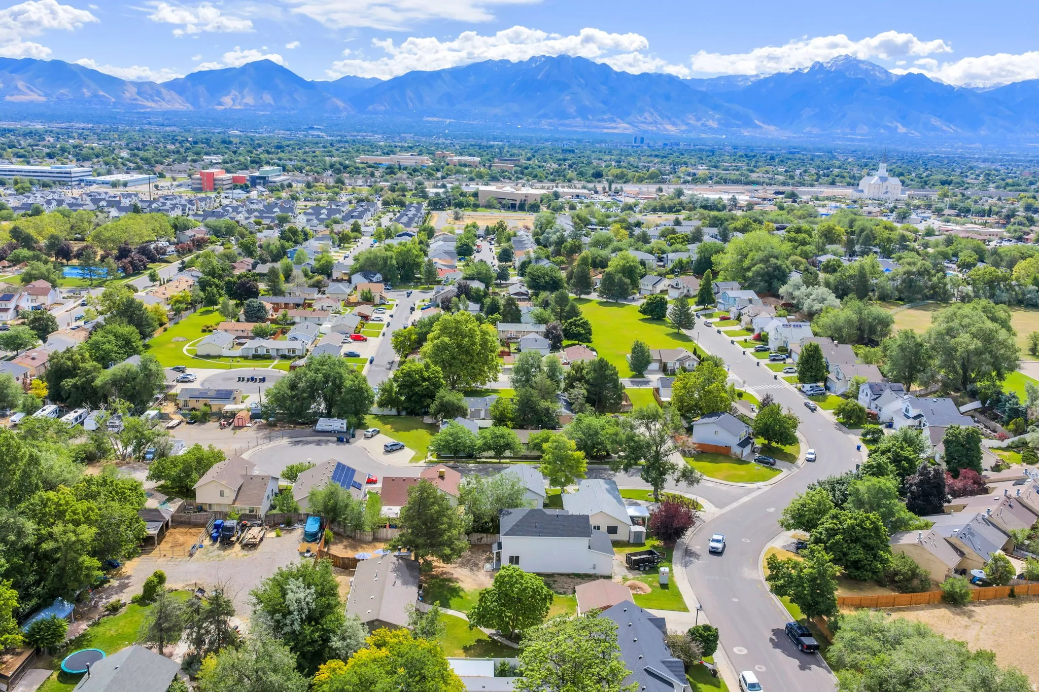 Aerial view showcasing a residential neighborhood with mature trees and a distant mountain range backdrop