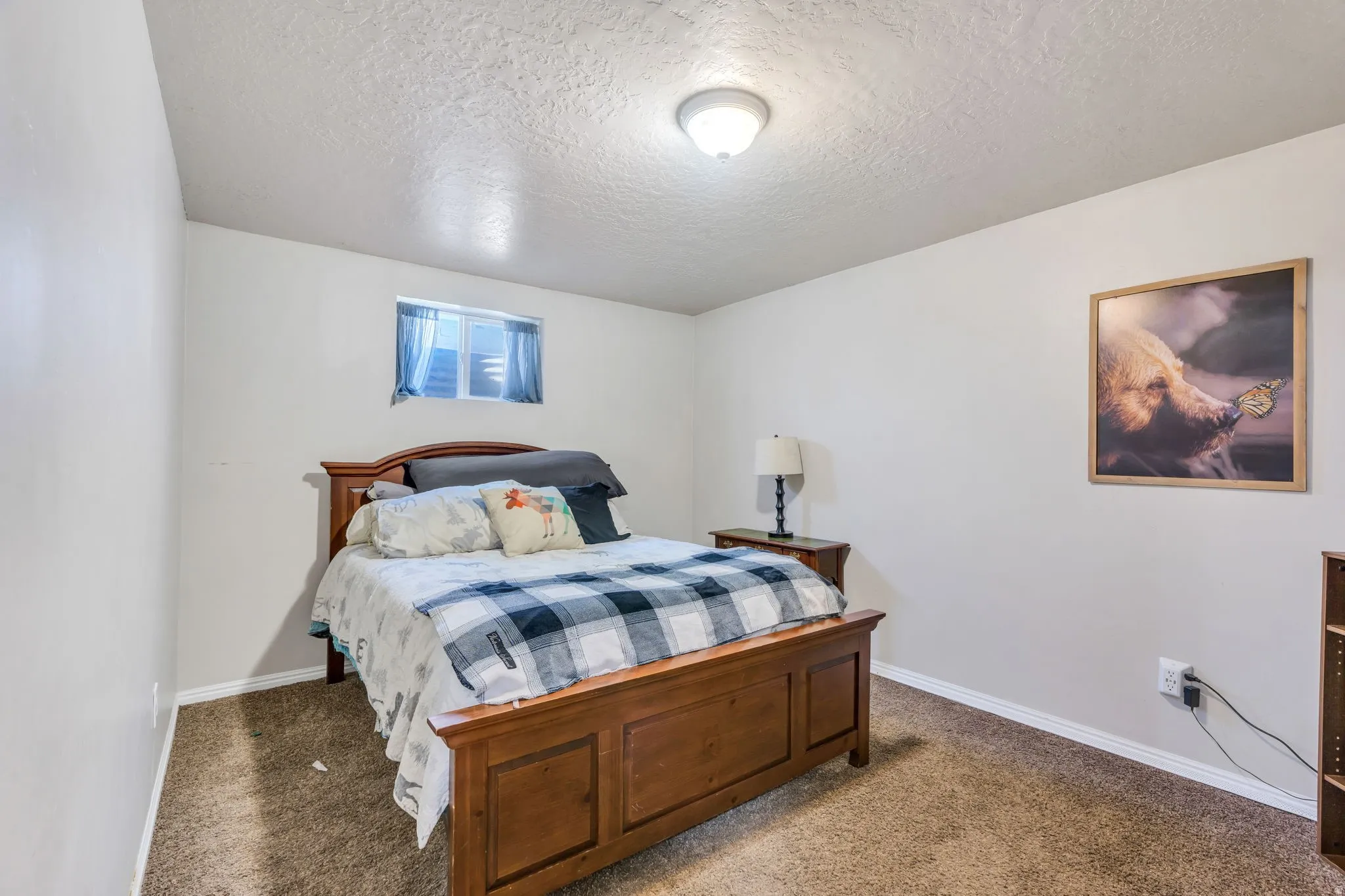 Carpeted room with a wooden bed frame, neutral wall paint, and a window with white blinds