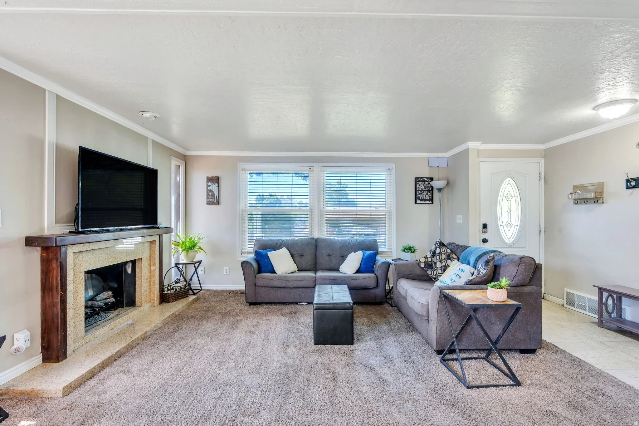Living area featuring a fireplace with a wood mantle and stone surround, neutral wall tones, white trim work, and carpeted flooring