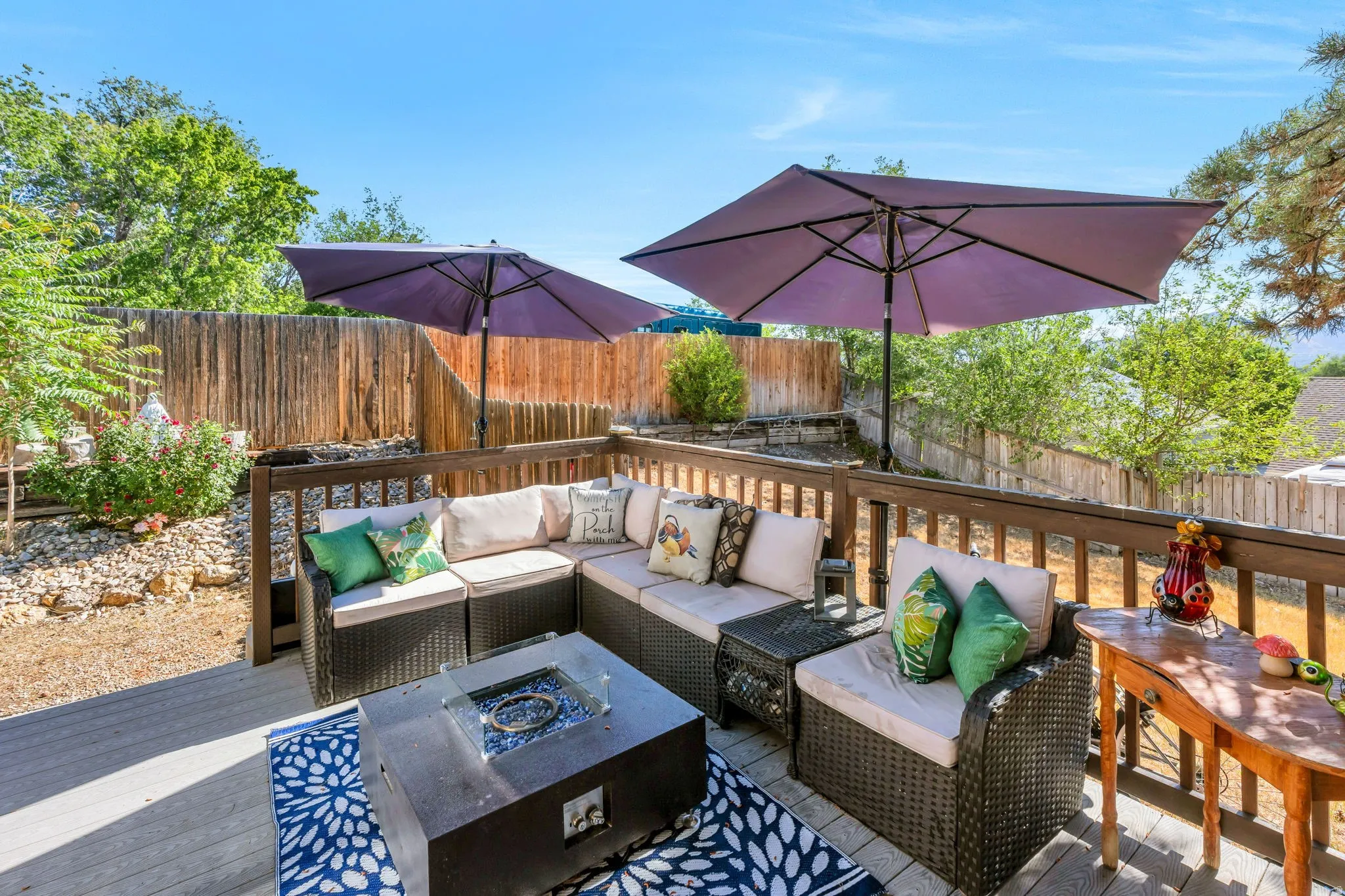 Expansive wood-finish deck featuring a built-in railing, privacy fencing, and surrounding landscaping